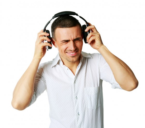 A man not enjoying what he is hearing, listening to music over white background