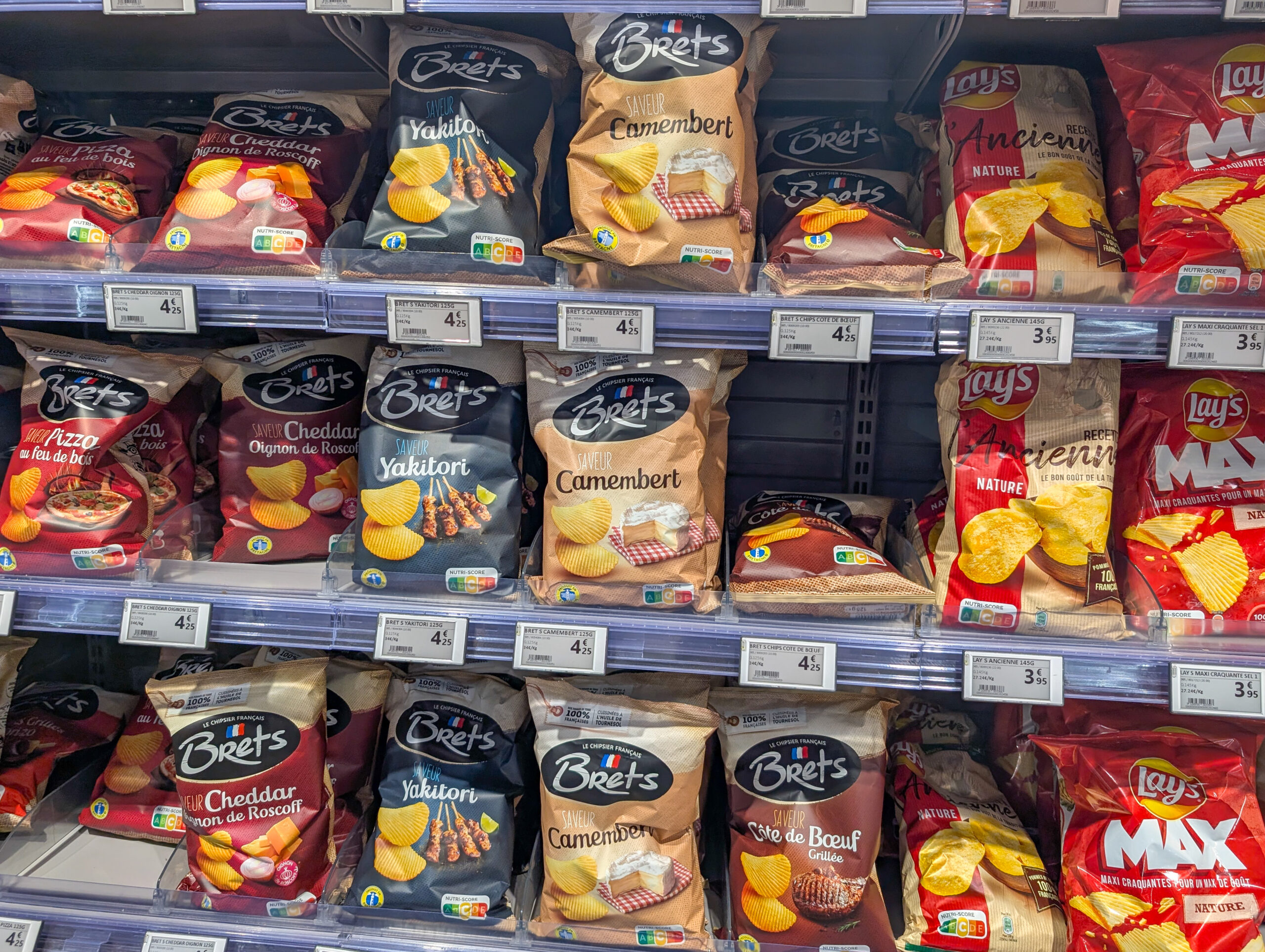 France, 21 December 2024 : Assorted flavored potato chips display in grocery store aisle 